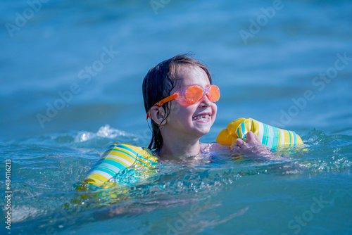 Happy child girl playing in the sea. Kid having fun outdoors. Summer vacation and healthy lifestyle concept.