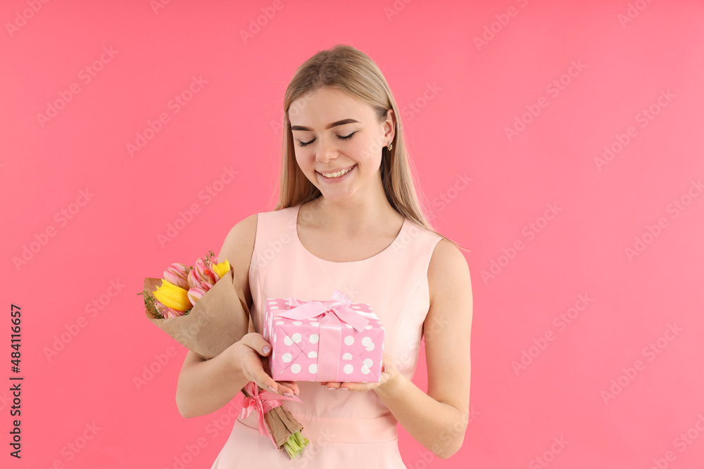 Young woman with bouquet and gift box on pink background Young woman with bouquet and gift box on pink background