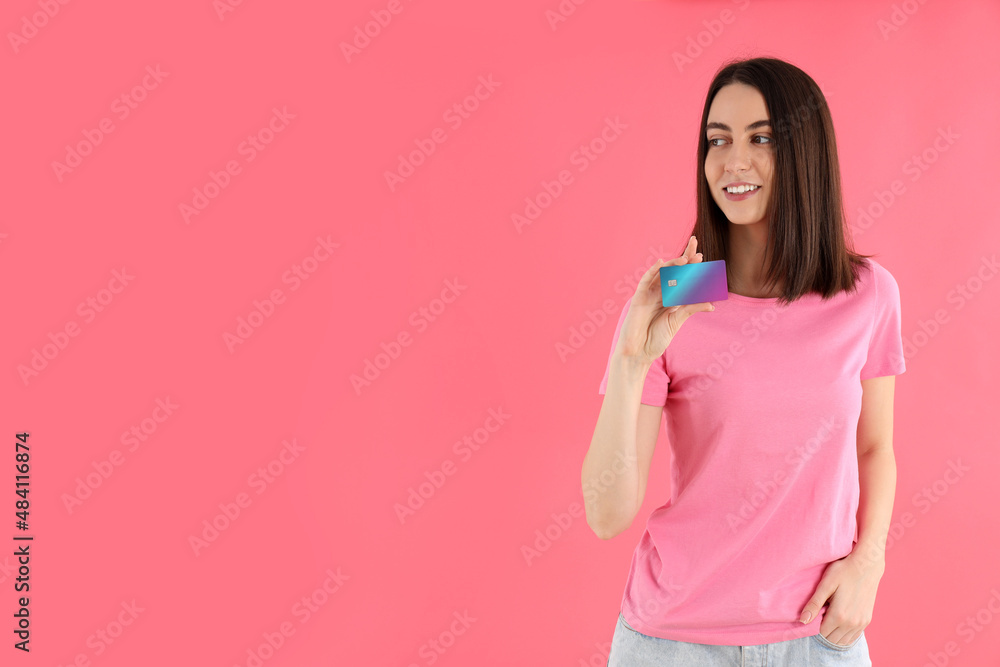 Attractive woman in t-shirt holds card on pink background Attractive woman in t-shirt holds card on pink background