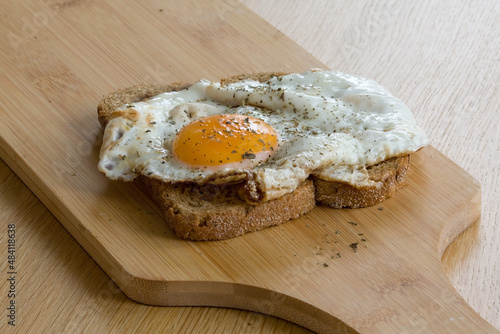 Slice of bread with baked egg on cutting board
