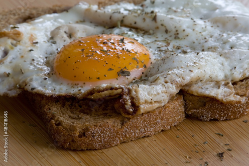 Slice of bread with baked egg on cutting board
