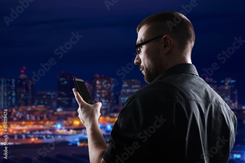 Man Using Smartphone Walking Through Night City Street. Stylish Man Using Mobile Phone,