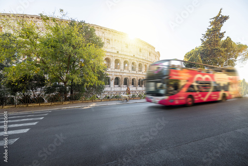 Fototapeta Naklejka Na Ścianę i Meble -  Street view with motion blurred tourist bus and Colosseum on background in Rome. Traveling Italian landmarks concept. Idea of tourist places and attractions