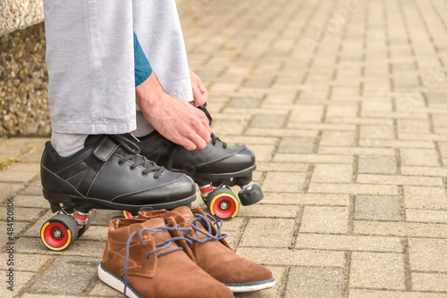 Man putting on roller skates. Changing casual shoes to roller skates before ride and training during summer leisure and recreation.