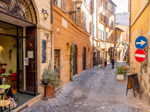 Fototapeta Naklejka Na Ścianę i Meble -  Narrow street with cafe and small shops in Rome. Italy travel concept, visiting cozy places