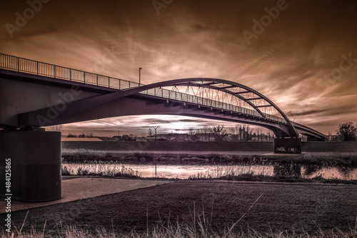 ogromny most nad rzeką i dramatyczne wieczorne niebo z zachodzącym słońcem