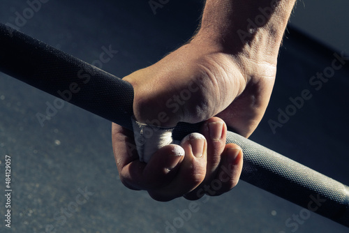 Close-up of man's right hand gripping a barbell with a hook grip
