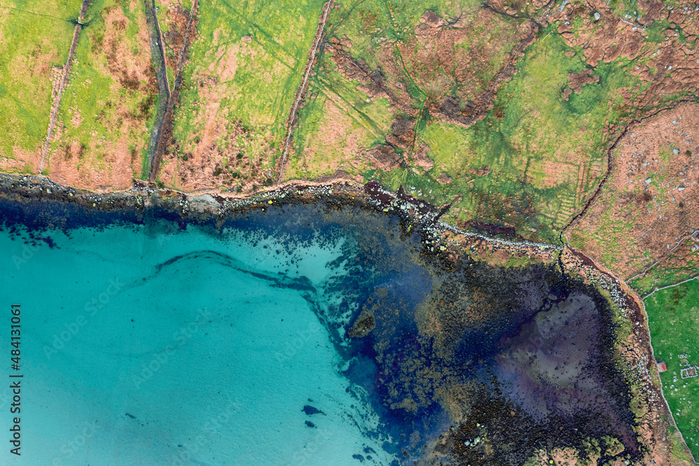 Aerial top down view on green fields separated by stone fences and beautiful ocean surface. West coast of Ireland. Irish nature landscape. Agriculture land by water