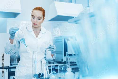 Professional female scientist is working on a vaccine in a scientific research laboratory. Genetic engineer workplace. Technology and science concept. Stop COVID-19