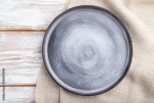 Empty gray ceramic plate on white wooden background. Top view.