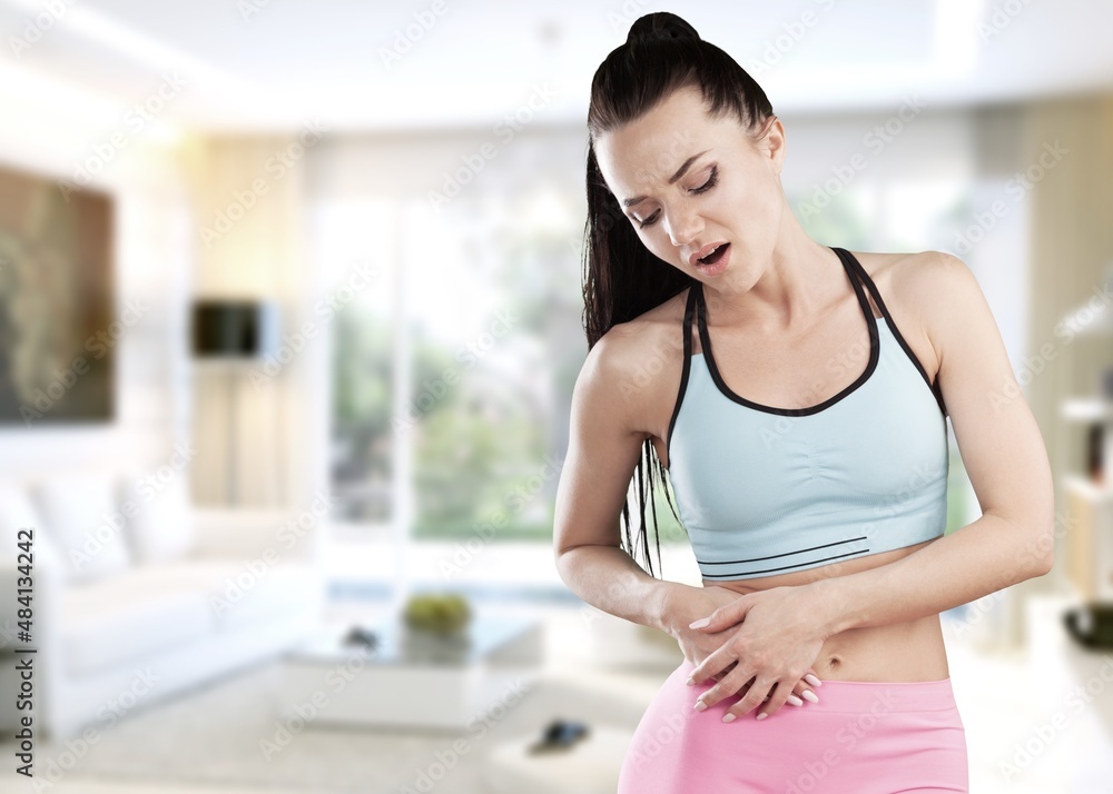 Young woman with arms on stomach and bending over with menstrual pain expression