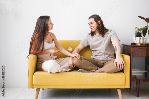 Couple sitting on yellow sofa in the room. Man and woman in love in a new apartment. Home comfort