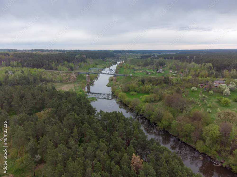 River among forest and railroad bridges across it, aerial view
