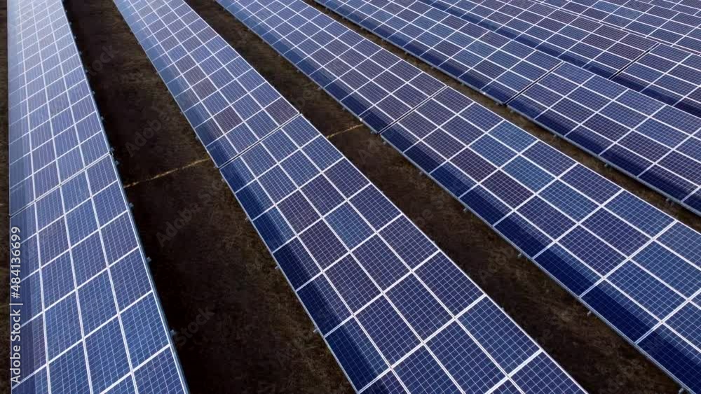 Aerial drone view flight over solar panels on sunny day close-up. Photovoltaic solar panel. Moving over solar panels with sun glare. Production of renewable alternative energy. Green ecological energy