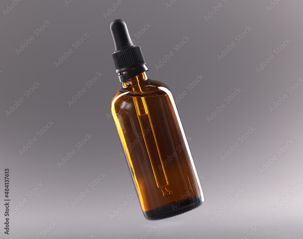 Fototapeta premium Glass bottle with cosmetic oil on gray background closeup