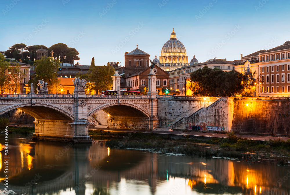 View of Rome with the Victor Emmanuel II bridge across the Tiber and the dome of St. Peter's cathedral in the Vatican from the Sant'Angelo bridge at sunset, Italy