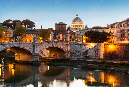 View of Rome with the Victor Emmanuel II bridge across the Tiber and the dome of St. Peter's cathedral in the Vatican from the Sant'Angelo bridge at sunset, Italy