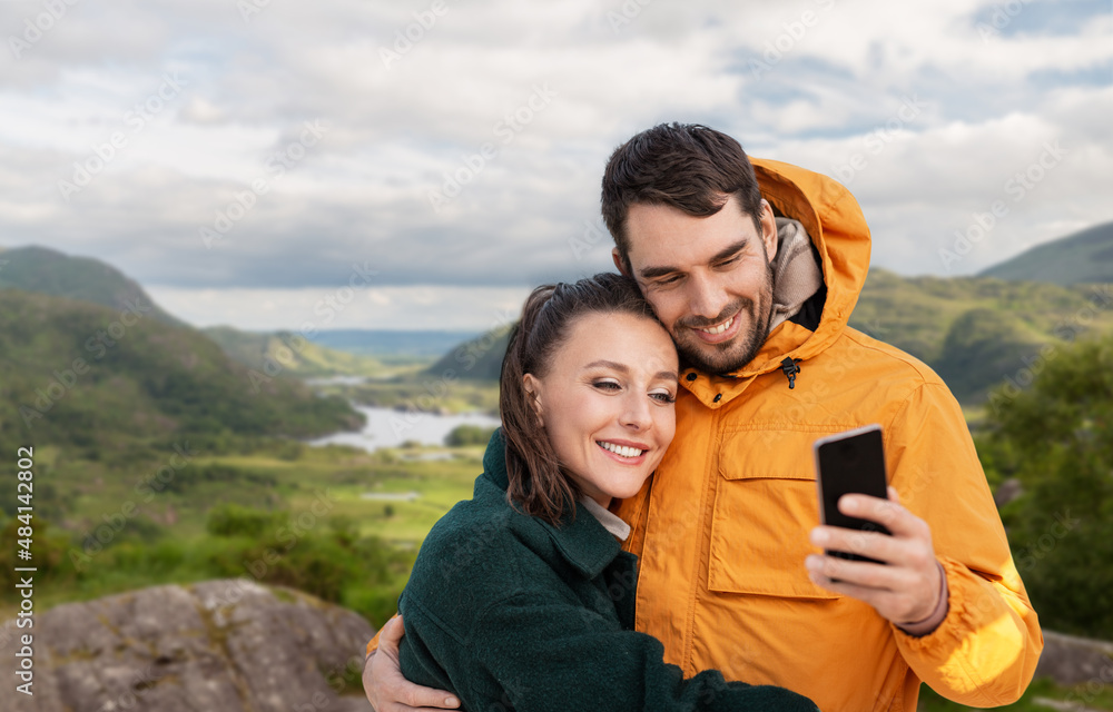 technology, travel and travel concept - happy couple with smartphone over river valley at Killarney National Park in ireland on background technology, travel and travel concept - happy couple with smartphone over river valley at Killarney National Park in ireland on background