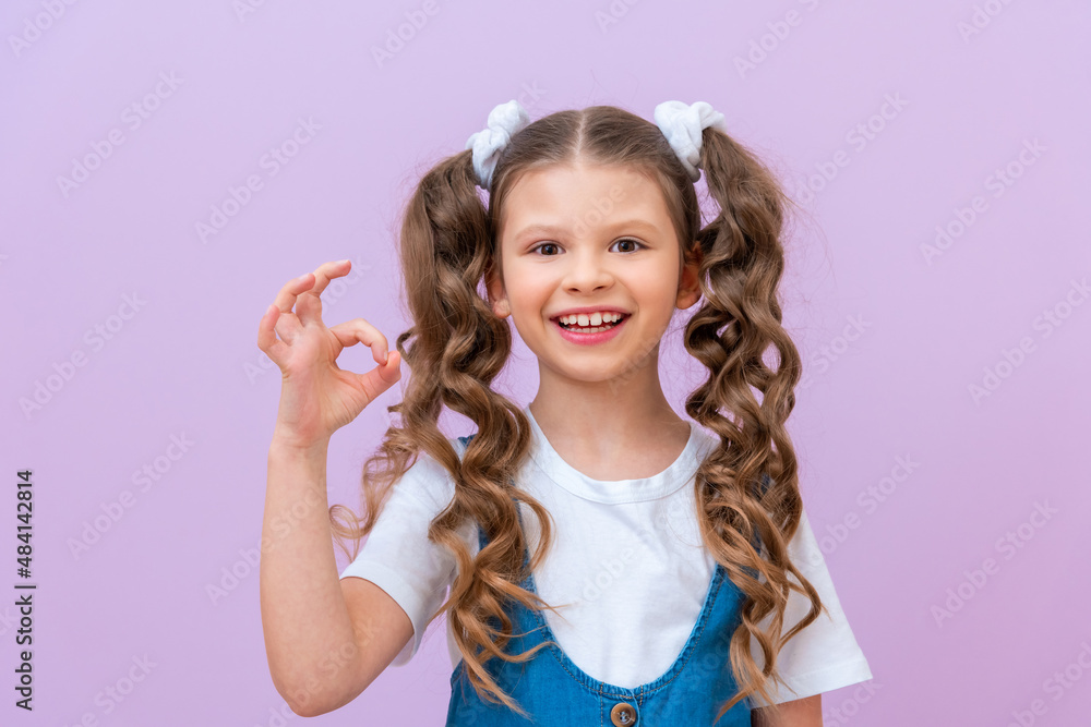 A happy young girl in a white T-shirt and a denim dress, shows the ok sign and smiles, Everything is fine, A happy young girl in a white T-shirt and a denim dress, shows the ok sign and smiles, Everything is fine,