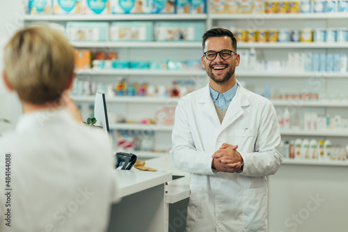 Happy young male pharmacist working with senior colleague in a pharmacy