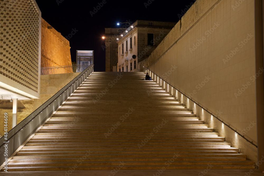 VALLETTA, MALTA - Valletta in night time on September 3, 2017. man sitting at Popular stairs near Malta Parliament in Valletta city, Malta