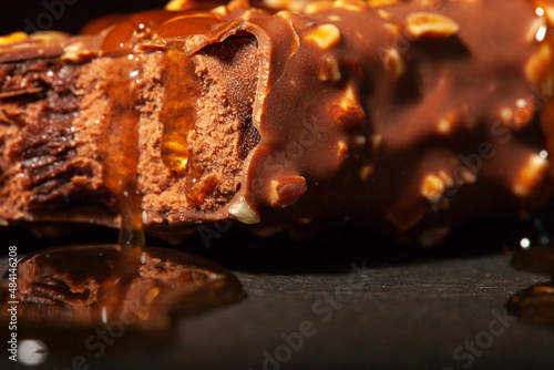 Bitten chocolate ice cream with almonds. Close-up. Against the background of black granite