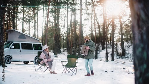 Couple of travellers resting in the woods on sunny winter day, enjoying van life. Couple of tourists living in a van with pop-up roof. Campers having lunch at the woods. High quality 4k footage