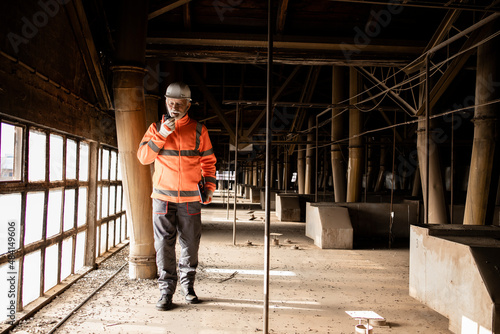 Industrial worker standing in production factory hallway.