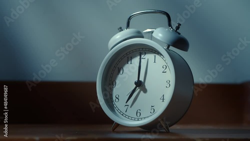 Close-up of a classic alarm clock set for seven o'clock in the morning. Man wakes up with an alarm clock early in the morning and turns off the alarm with his hand.