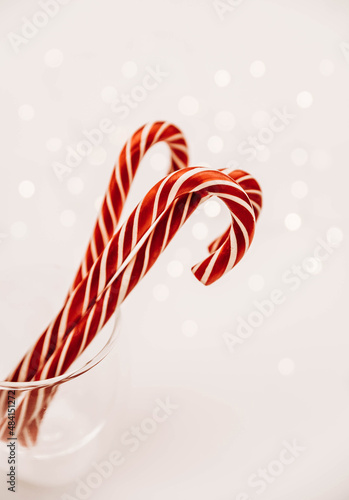 candy cane isolated on white background. cane in a transparent glass against the background of lights. sweets on the white table