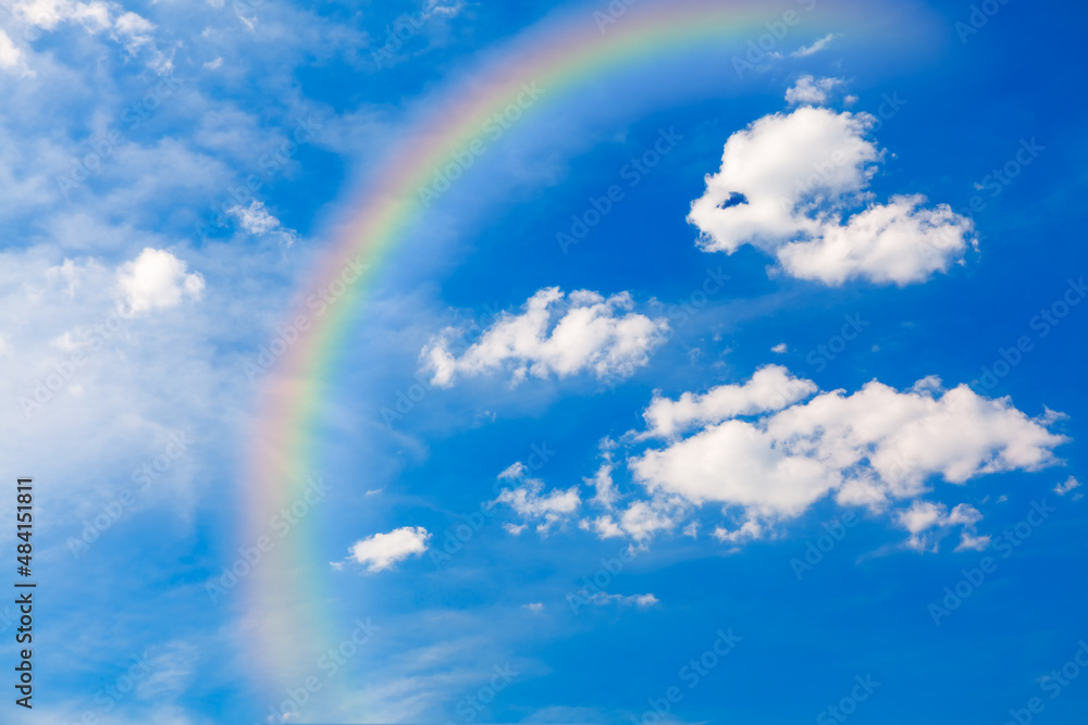 Rainbow at summer sky . Rainbow with white clouds at blue sky Rainbow at summer sky . Rainbow with white clouds at blue sky
