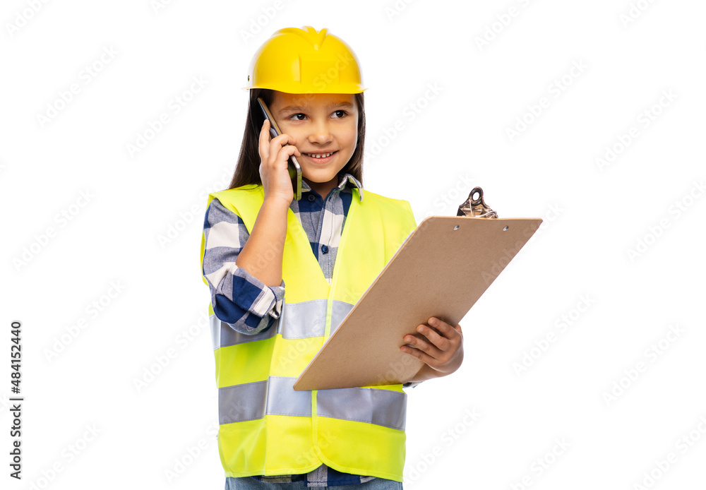 building, construction and profession concept - smiling little girl in protective helmet and safety vest with clipboard calling on smartphone over white background