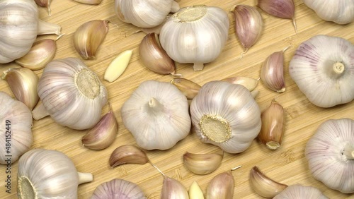 Fresh garlic bulbs and cloves on a wooden table, rotation background. Loop motion