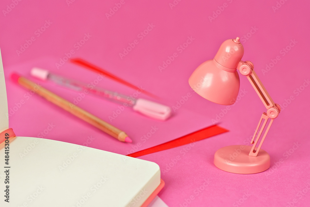 Notepad on a pink background. Toy table lamp near the notebook. Copy space and free space for text near the lamp. The concept of roochy space and creative ideas. Notepad on a pink background. Toy table lamp near the notebook. Copy space and free space for text near the lamp. The concept of roochy space and creative ideas.