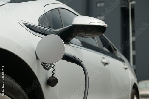 EV charging technology. Power supply is connected to the electric vehicle to charge the battery. Plug-in hybrid vehicle supplies power