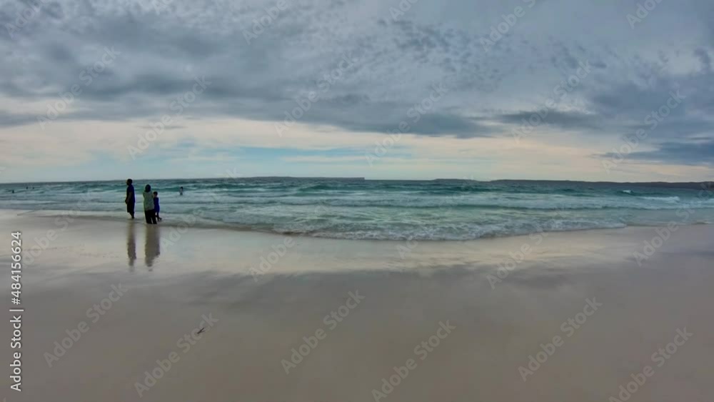 White Sands Hyams Beach, Jervis Bay in Australia under dark clouds with sea waves, people swimming and walking on the beach White Sands Hyams Beach, Jervis Bay in Australia under dark clouds with sea waves, people swimming and walking on the beach