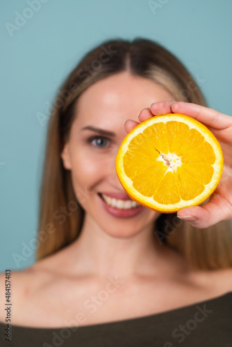Close-up portrait of topless woman with perfect skin and natural make-up, full nude lips, holding fresh citrus vitamin C orange