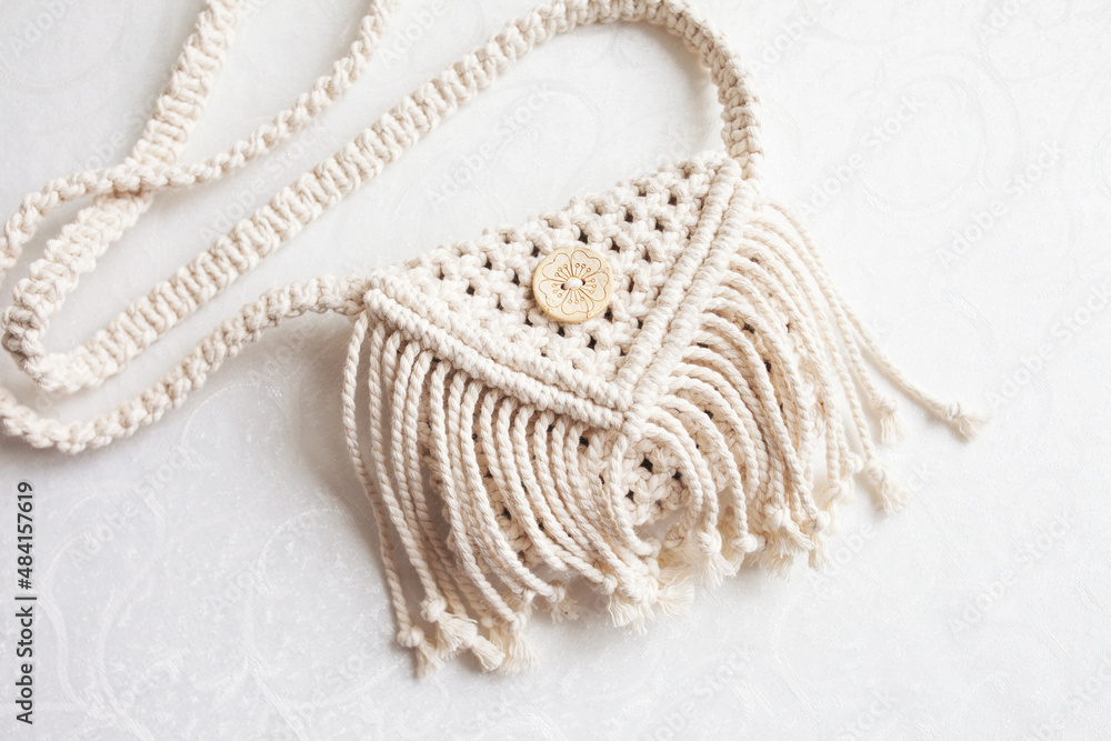 Handmade white macrame bag on the linen background, ECO friendly. Hobby knitting handmade macrame. Modern summer concept. Copy space Handmade white macrame bag on the linen background, ECO friendly. Hobby knitting handmade macrame. Modern summer concept. Copy space