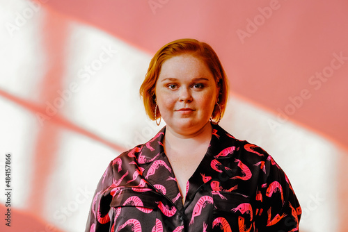 smiling young milennial woman posing in studio over pink background photo