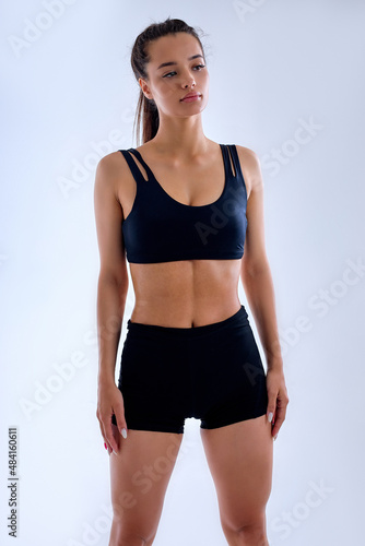 Tired fit caucasian woman in black sportswear after sport exercises, looking at side, posing at camera, exhausted athlete female in bblack short top and shorts having rest, relaxing. portrait photo