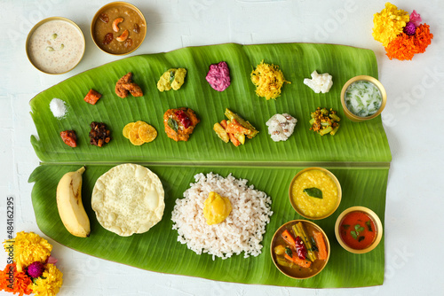 Traditional Onam sadhya rice Sambar, Rasam, parippu dal curry ghee Pappadom Payasam on banana leaf Onam Vishu Pongal Diwali festival vegetarian food Kerala Tamil Nadu South India.