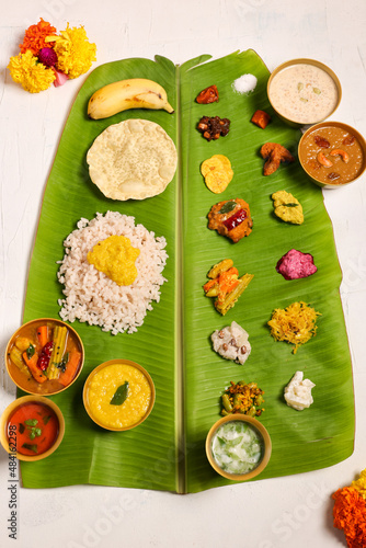 Traditional Onam sadhya rice Sambar, Rasam, parippu dal curry ghee Pappadom Payasam on banana leaf Onam Vishu Pongal Diwali festival vegetarian food Kerala Tamil Nadu South India.