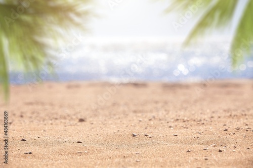 Beautiful background for summer vacation and travel. Sand of tropical beach, blurry palm leaves
