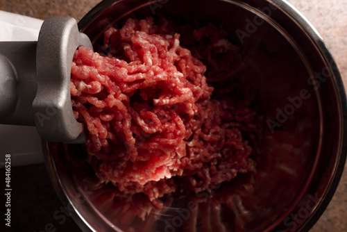 Process of preparing forcemeat by means of a meat grinder. Fresh red mincing close-up on black background with copy space. Selective focus