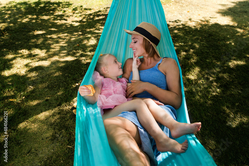 loving family spends time together in summer time enjoy the little things. slow life. mom and little daughter relax in a hammock in the summer in the garden 