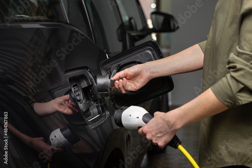 Close Up Of Woman's hands removing the lid of an electric car at home.