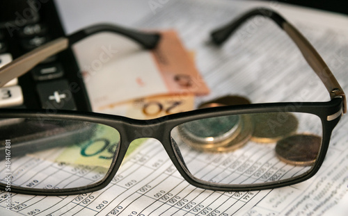Glasses, Belarusian money, a calculator and a receipt for payment of housing and communal services in Belarus. Price increase concept. Blurred background. Close-up. Selective focus, narrow focus.