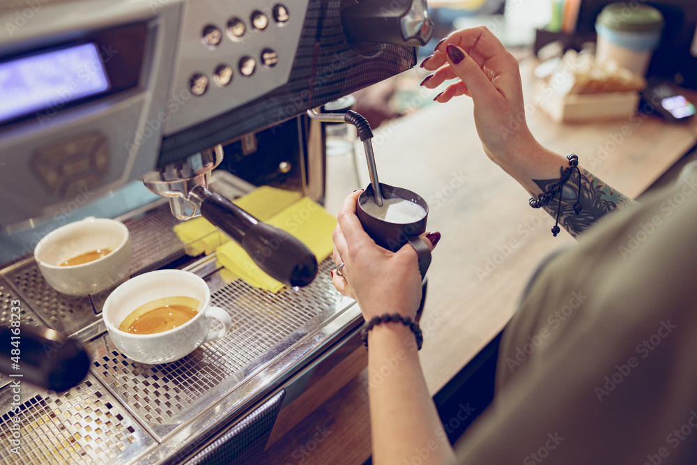 Female barista using coffee machine in coffee shop