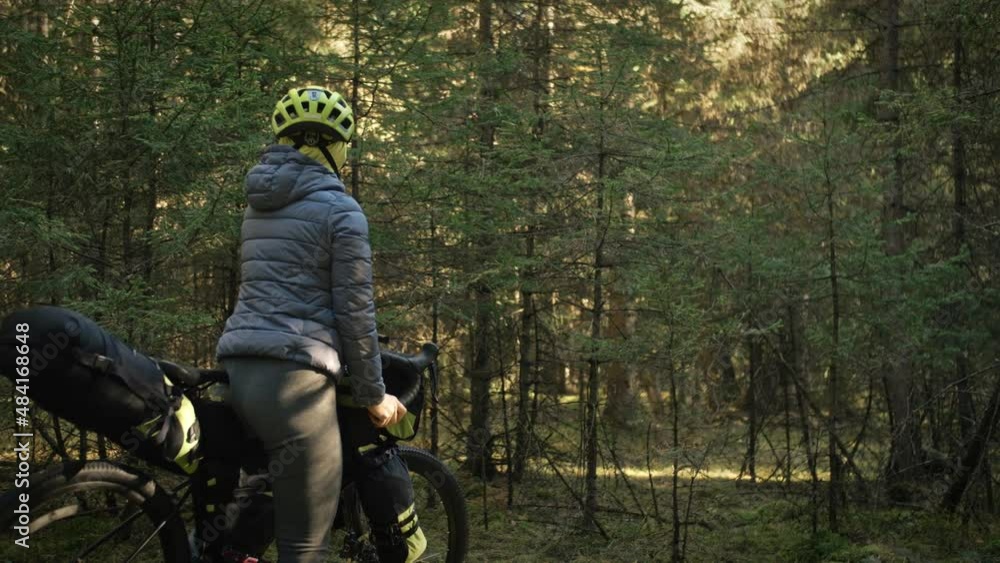 The woman travel on mixed terrain cycle touring with bike bikepacking. The traveler journey with bicycle bags. Magic forest park. The woman travel on mixed terrain cycle touring with bike bikepacking. The traveler journey with bicycle bags. Magic forest park.