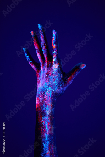 raising up hand depicts the power or rising of human emotion, fluorescent art. cropped female hand under neon light portrays the power, rising of something or person emerging out of his old customs